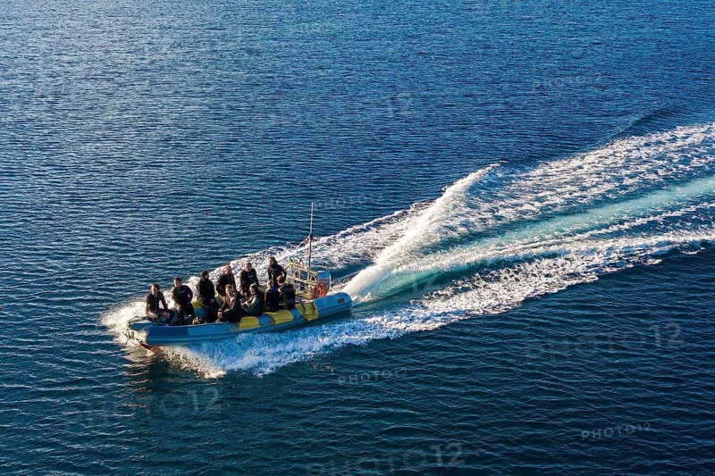 Bird's eye view of diving boat inflatable boat in fast motion with scuba diver on board