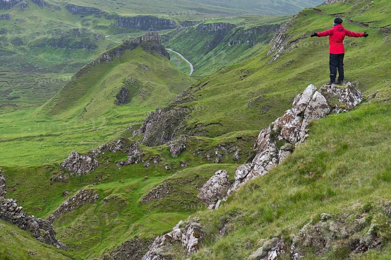 Hiker in red outdoor jacket in the bizarre rock world of Quiraing