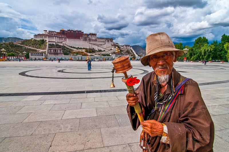 Pigrim with praying wheel before the Potala in Lhasa
