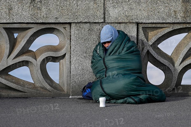 Homeless person with sleeping bag and cup