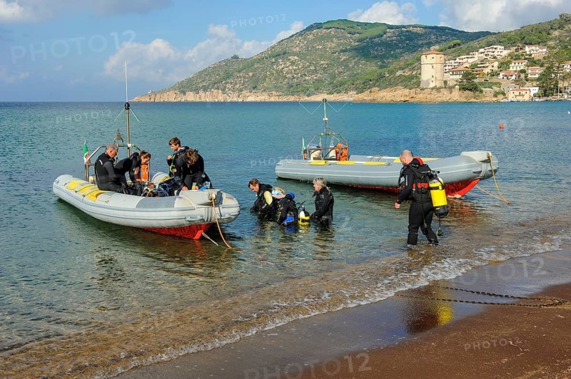 Divers on the beach getting into diving boats inflatables