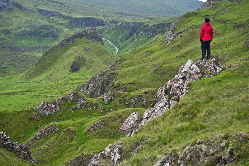 Hiker in red outdoor jacket in the bizarre rock world of Quiraing