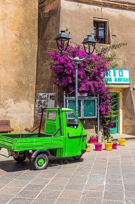 Green Piaggio Ape utility vehicle in front of the cathedral of Rio nell Elba