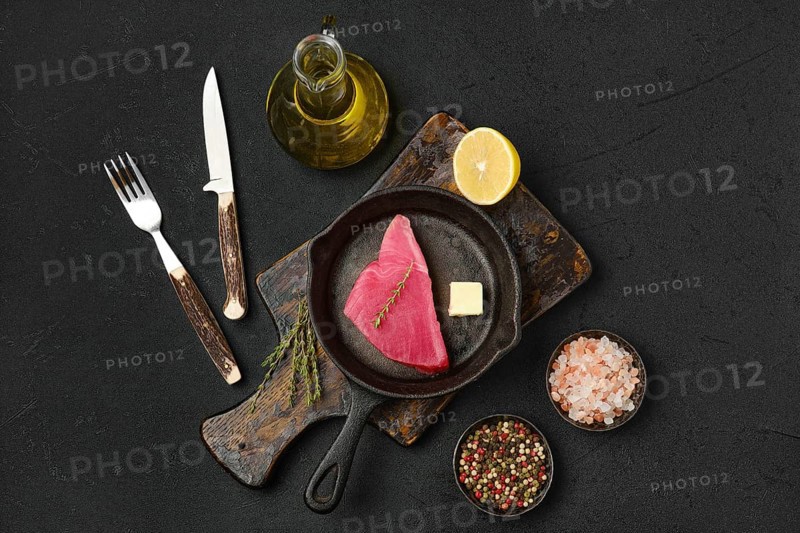 Top view of raw fresh tuna steak in cast iron skillet and spices