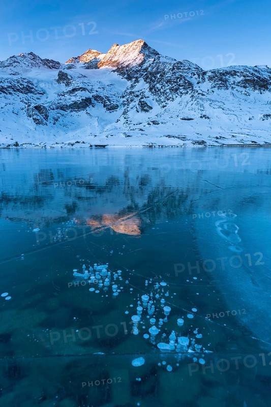Frozen air bubbles in the black ice of the frozen Lago Bianco in the Swiss mountains