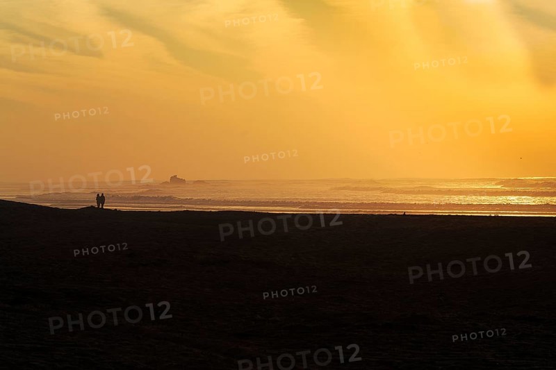Couple on the beach looking at the ruins of the watchtower Bordj El Berod on the horizon