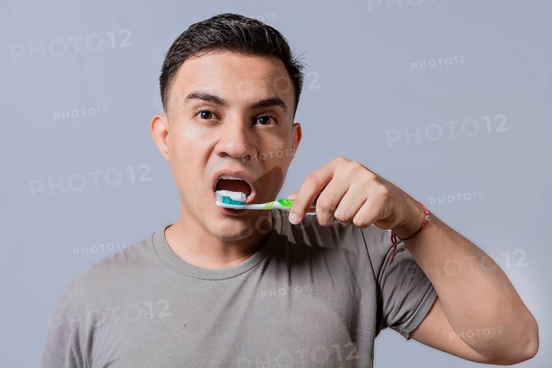Handsome guy brushing his teeth isolated