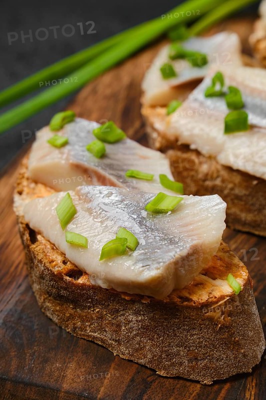 Closeup view of sandwich with salty herring and spring onion