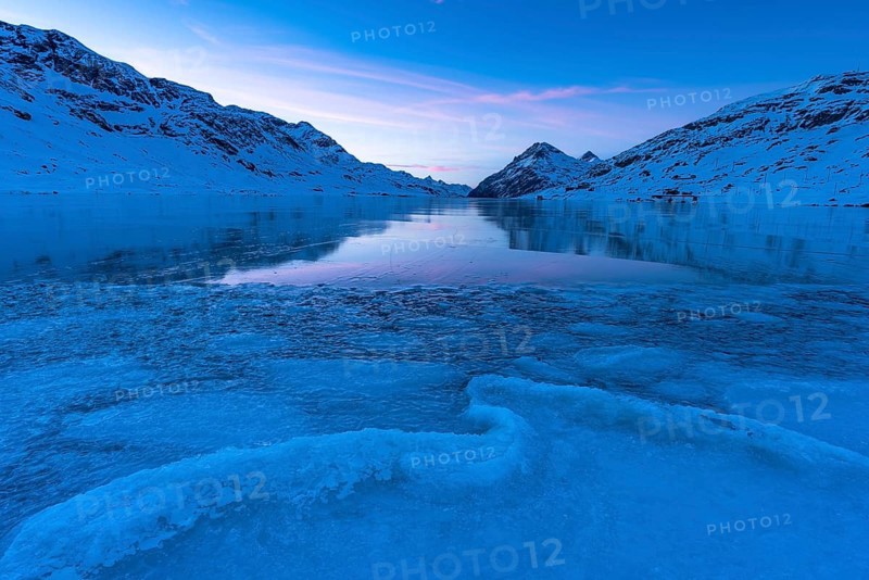 Ice structures in the black ice of the frozen Lago Bianco in the Swiss mountains in the evening light