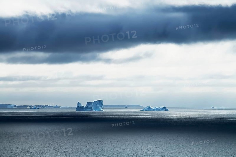 Icebergs drifting on the open sea against a dark cloudy sky