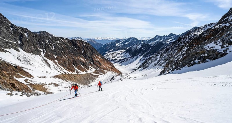 Two ski tourers walking on the rope on the glacier