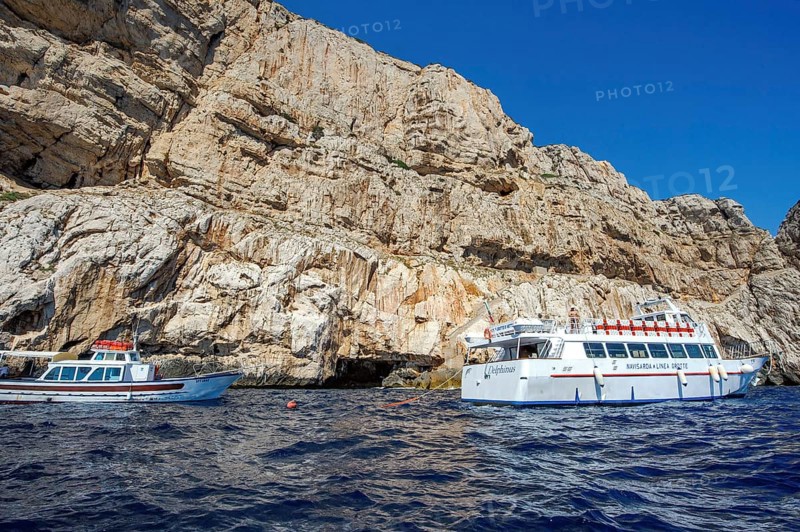 Excursion boats in front of rocky coast of Capo Caccia with Grotta Nereo cave