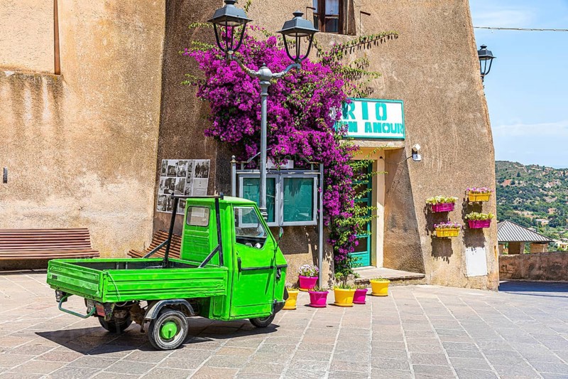 Green Piaggio Ape utility vehicle in front of the cathedral of Rio nell Elba