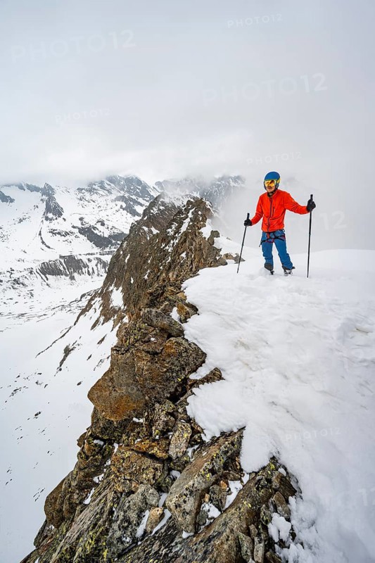 Ski tourers on rocky ridge with snow