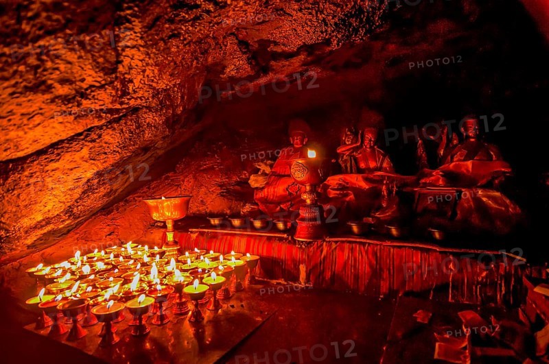 Cave with candles and Buddha images along the Kailash Kora