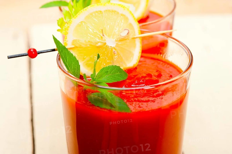 Fresh tomato juice gazpacho soup on a glass over white wood table