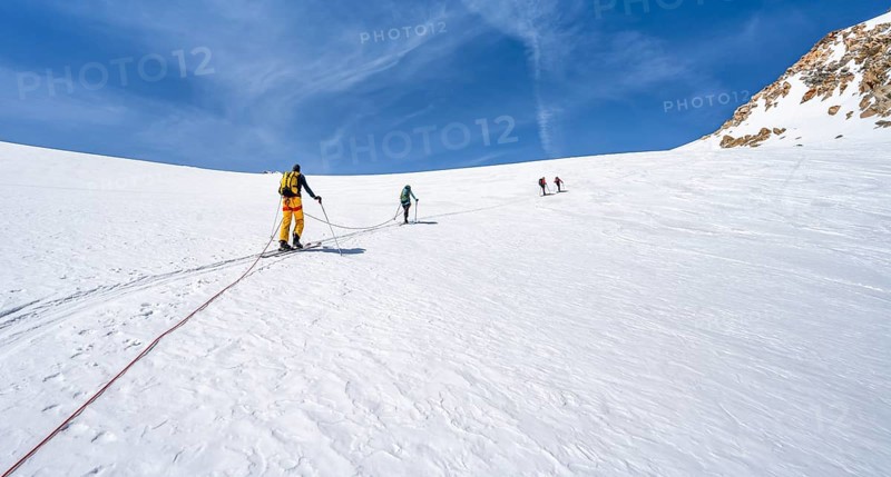 Ski tourers walking on the rope on the glacier