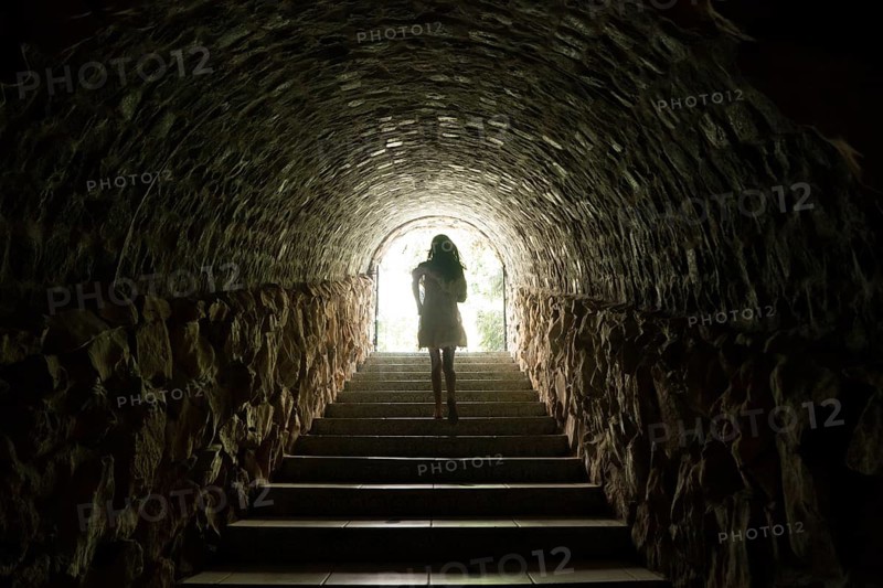Girl walking throug dark tunnel into light