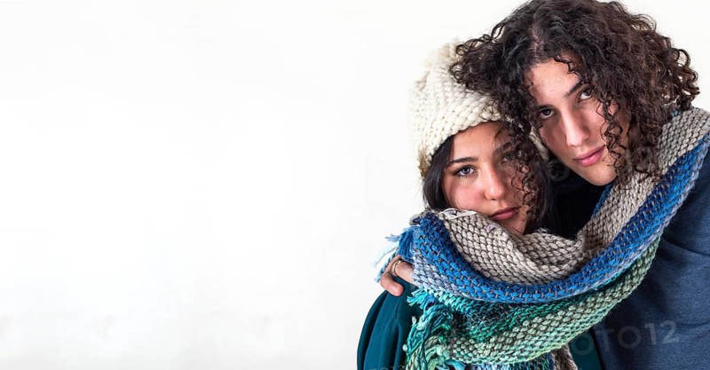 Two friends are hugging each other like they are cold while wearing the same scarf. Winter concept