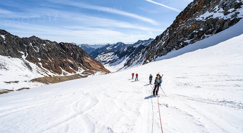 Group of ski tourers walking on the rope on the glacier
