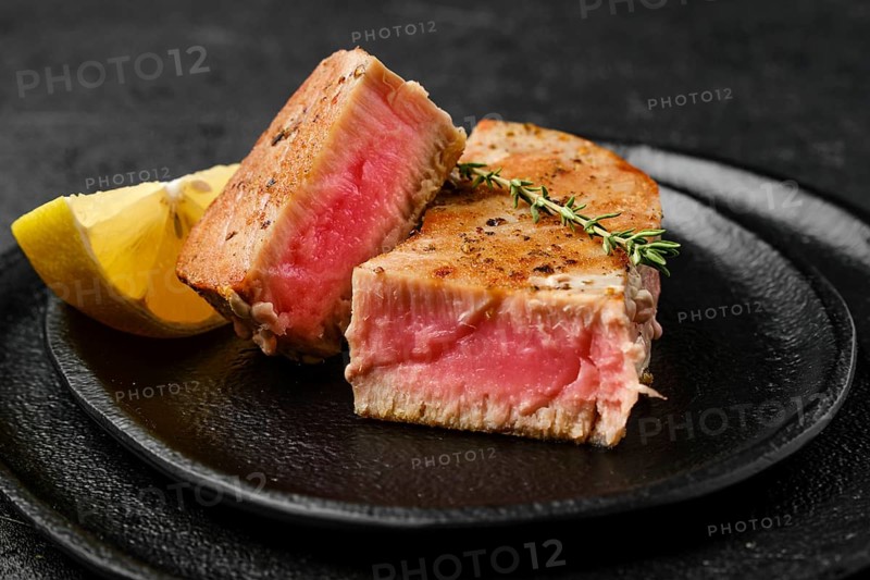 Closeup view of fried tuna steak on slate plate