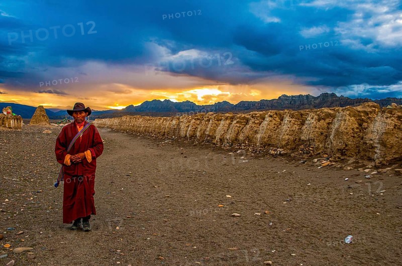 Monk walks along an eroded mud wall in the kingdom of Guge