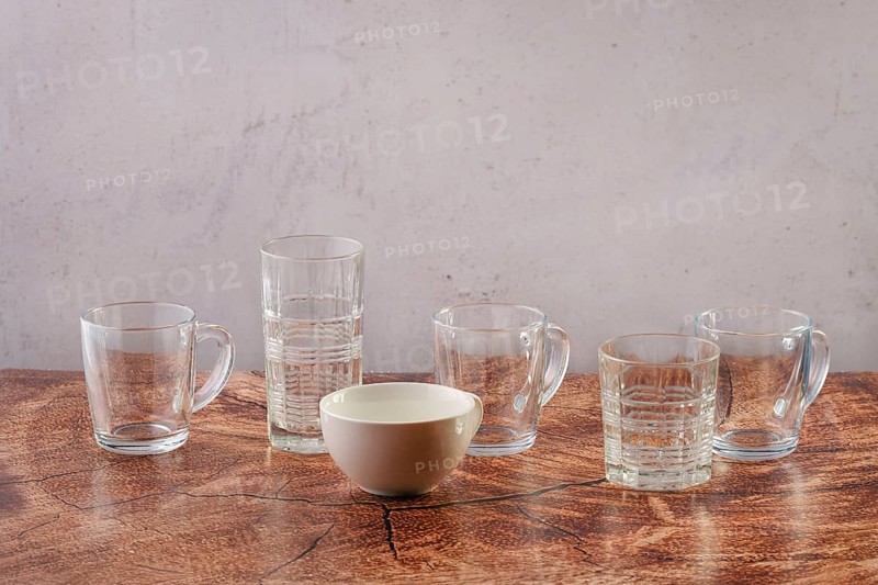 Empty glasses and cups of different forms and shapes on wooden tabletop