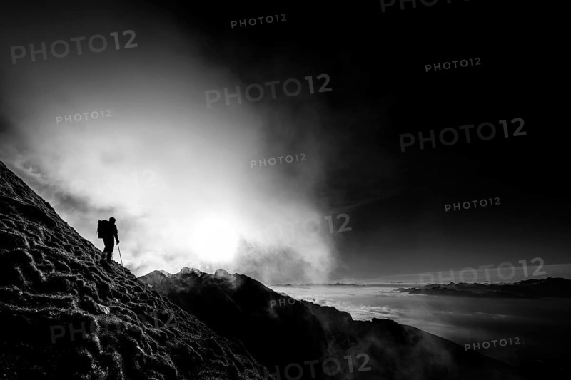 Mountaineer on mountain slope with fog against the light