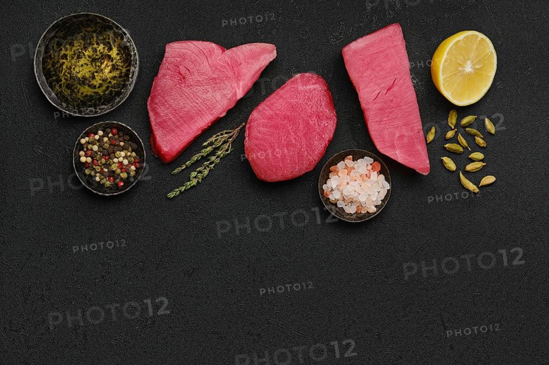 Top view of raw fresh tuna steak and spices on black background