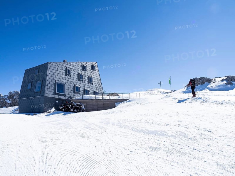 Snowshoe hiker in front of mountain hut