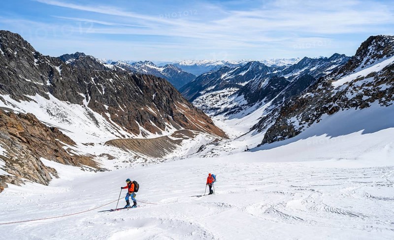 Two ski tourers walking on the rope on the glacier