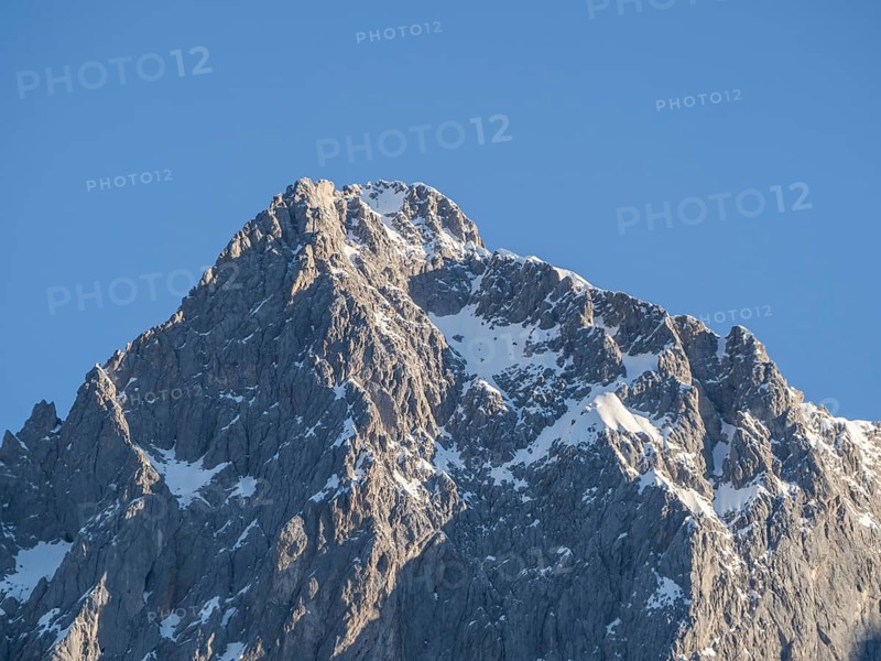 Blue sky above snowy alpine peak