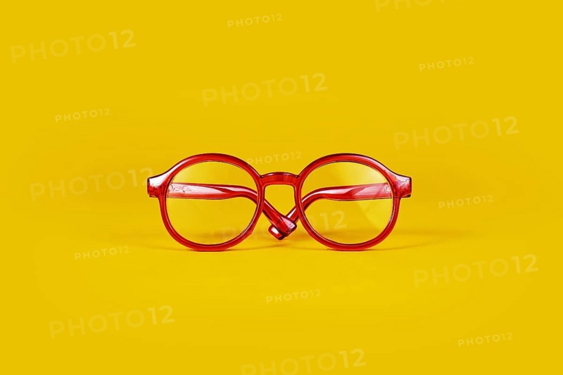 Small red round eye glasses on yellow background