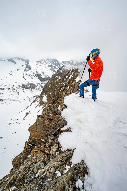 Ski tourers on rocky ridge with snow