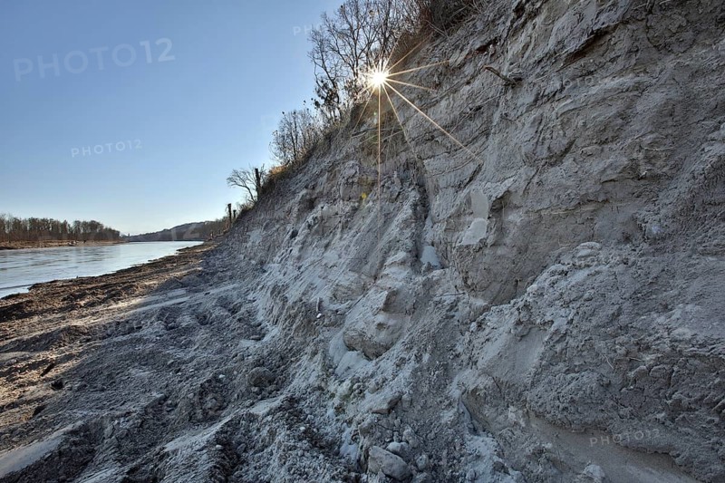 Steep wall of sand and dredge marks on a river bank