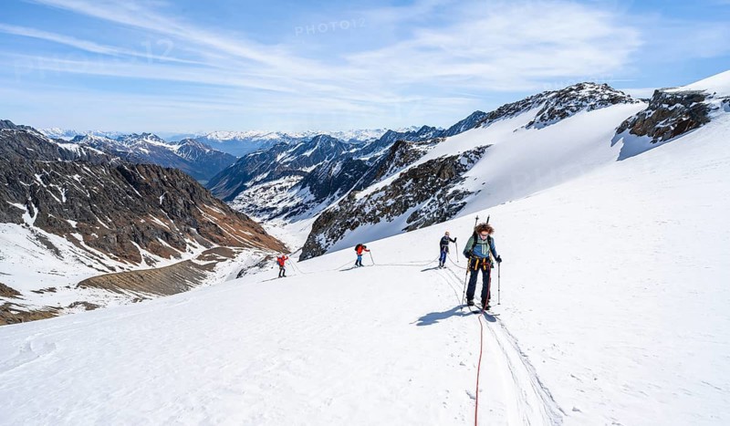 Ski tourers walking on the rope on the glacier