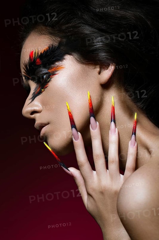 Beautiful girl in the image of the Phoenix bird with creative makeup and long nails. Manicure design. The beauty of the face. Photos shot in studio