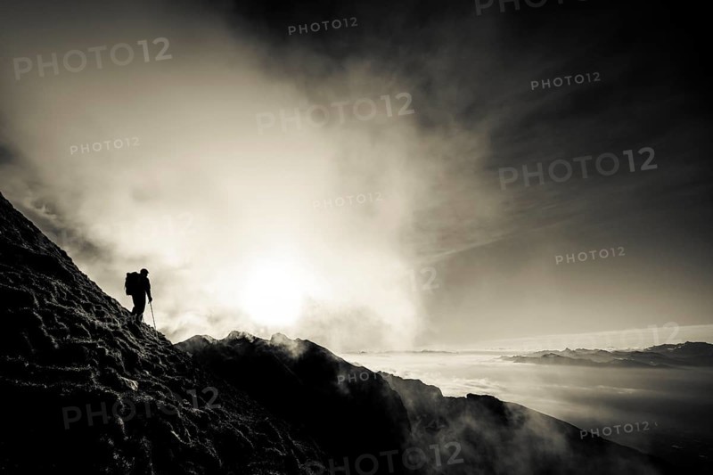 Mountaineer on mountain slope with fog against the light