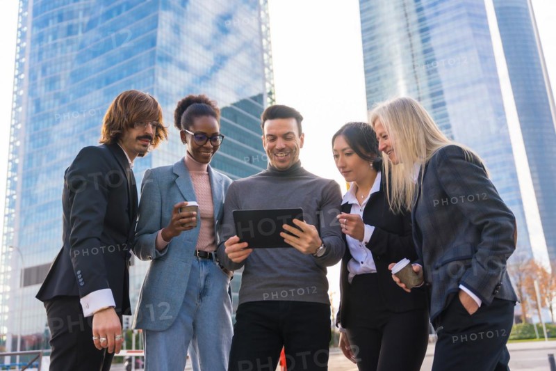 A group of multi-ethnic business people in a business park looking at a tablet