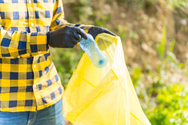 Unrecognizable person collecting plastics in a forest. Ecology concept