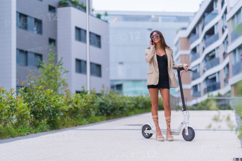A businesswoman moving with an electric scooter around the city