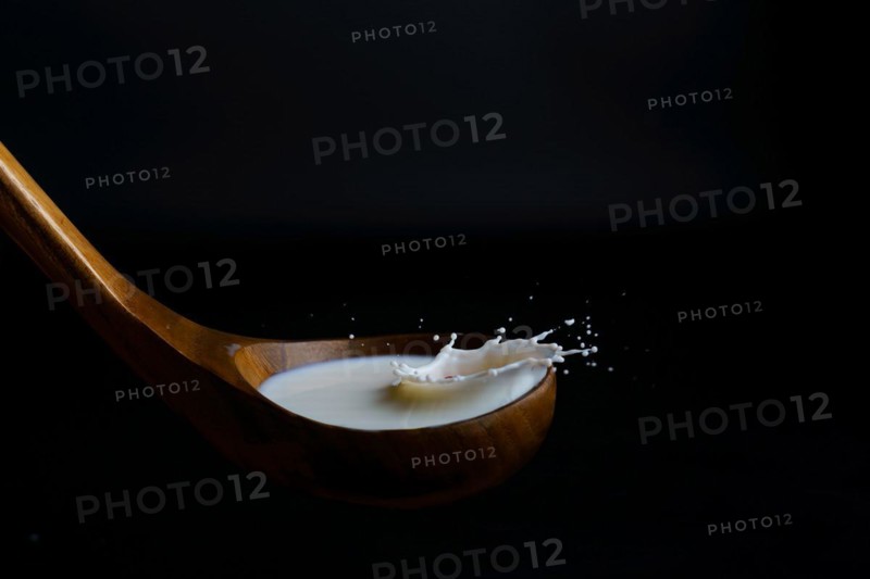 Milk splashing on a wooden ladle