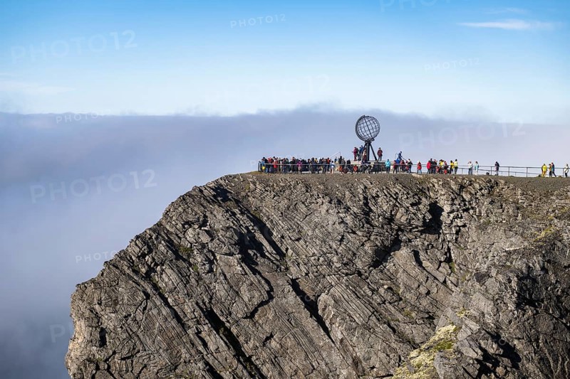 Rock cliff of the North Cape with steel globe at midnight sun