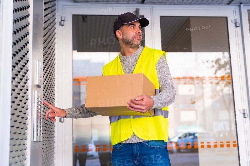 A young delivery man in a protective uniform delivering the online order in a home ringing the doorbell