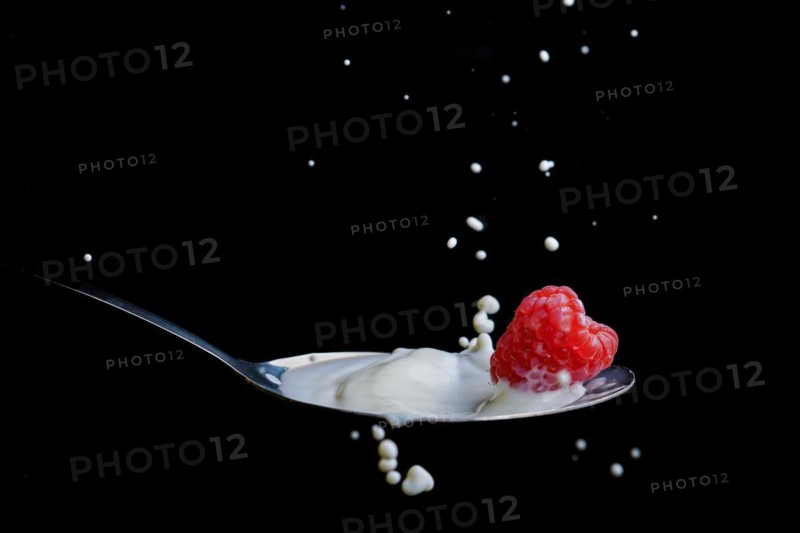 Raspberry splashing milk on a metal spoon splash effect with black background
