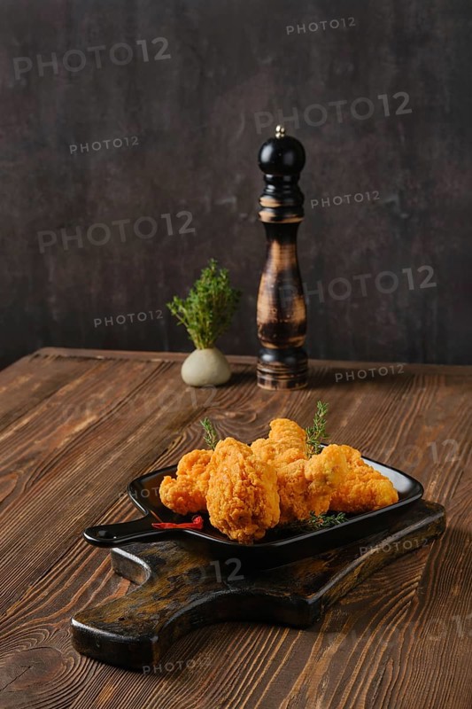 Spicy deep fried breaded chicken wings on shabby serving board
