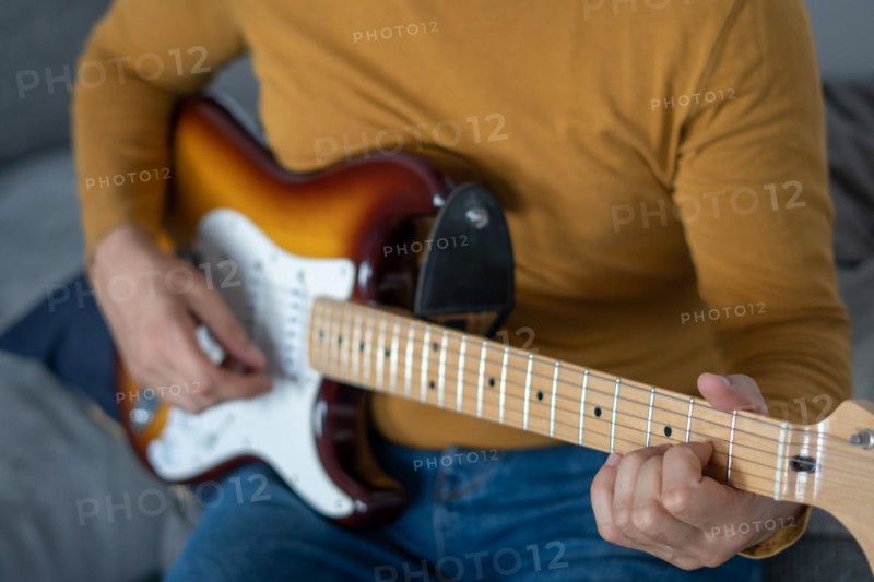 Young boy with beard playing guitar at home