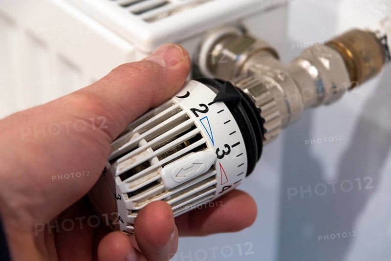 Man's hand turns thermostat