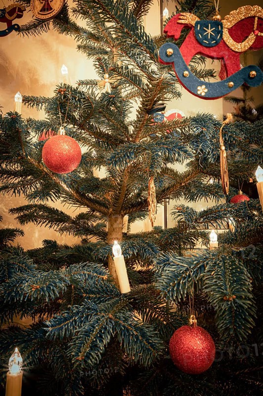 Red Christmas tree balls on a Christmas tree and a rocking horse made of felt with Christmas tree lights