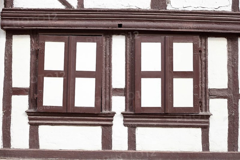 Window shutters closed on a white house wall with half-timbered beams